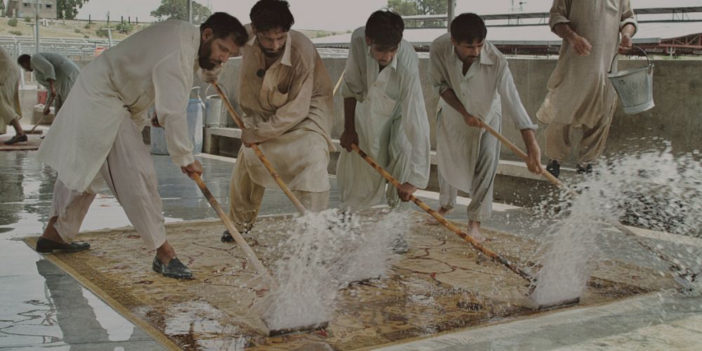 Handmade rug being washed by artisans during the finishing process
