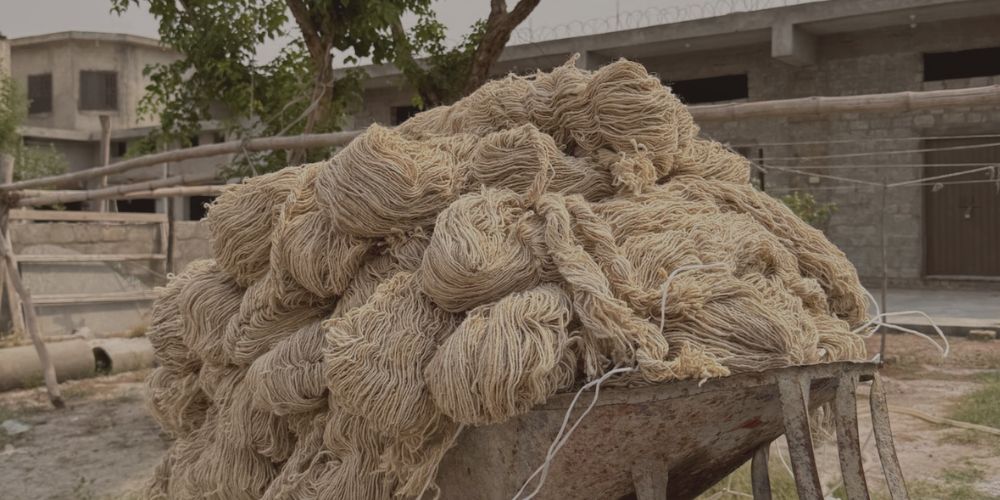 Bundles of natural wool yarn piled in a wheelbarrow during early stages of rug production
