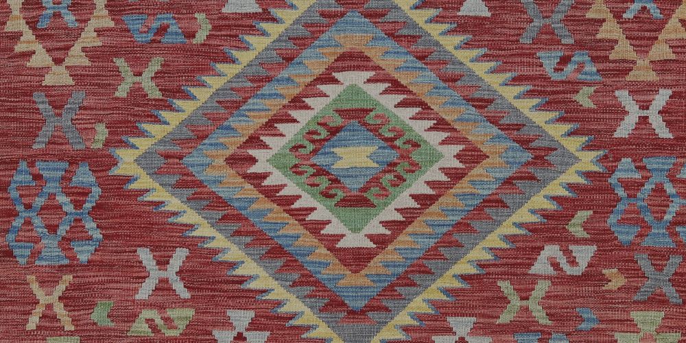 Handmade kilim rug with bold geometric pattern in red and soft natural tones